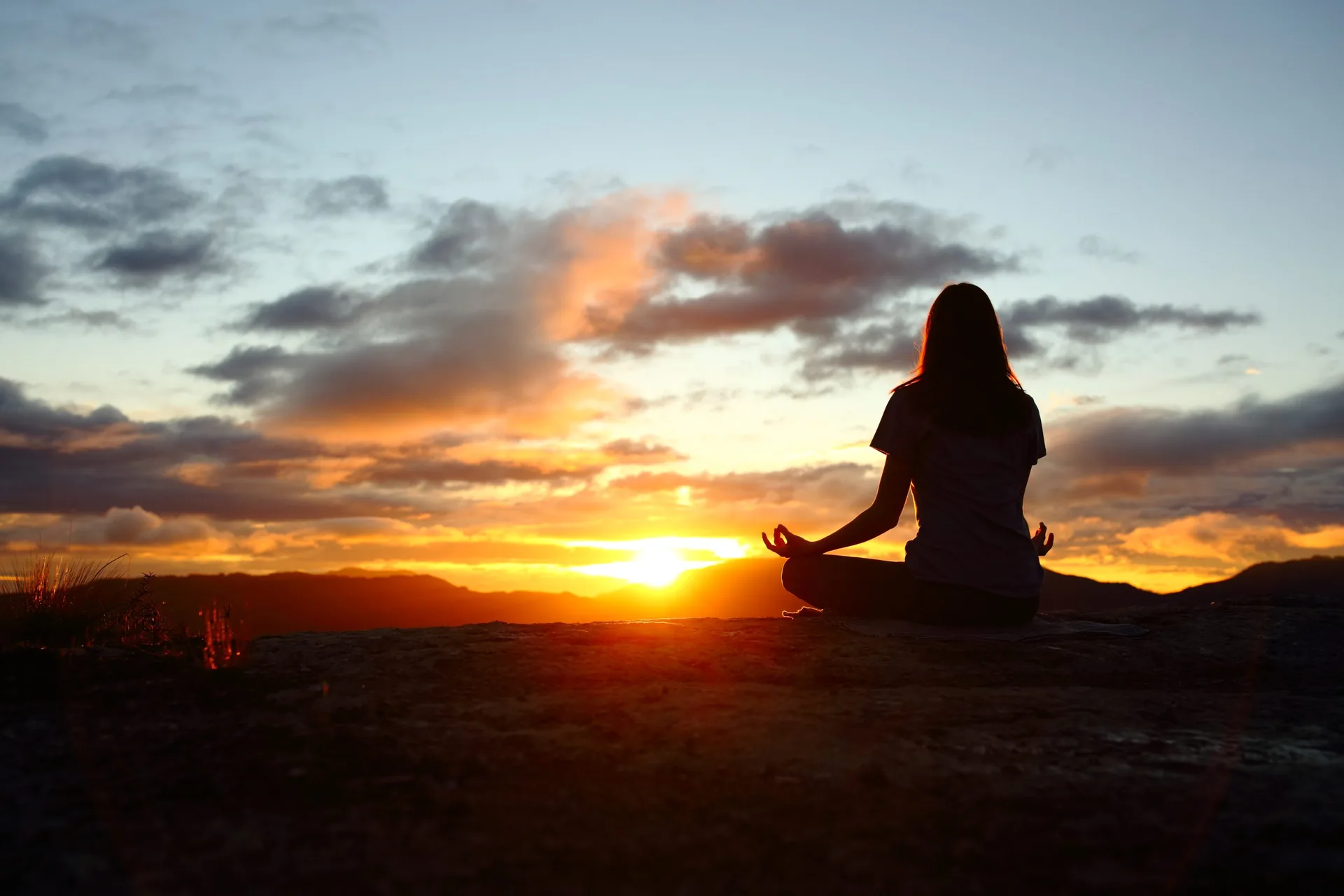 Back-view-portrait-of-a-woman-silhouette-doing-yoga-at-sunset-in-the-mountain