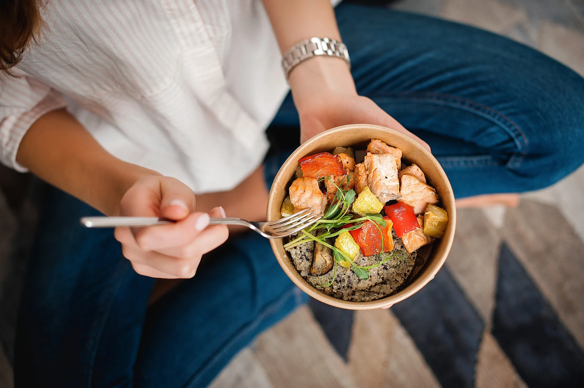 Girl-holds-a-paper-plate-with-healthy-food-sitting-on-the-floor