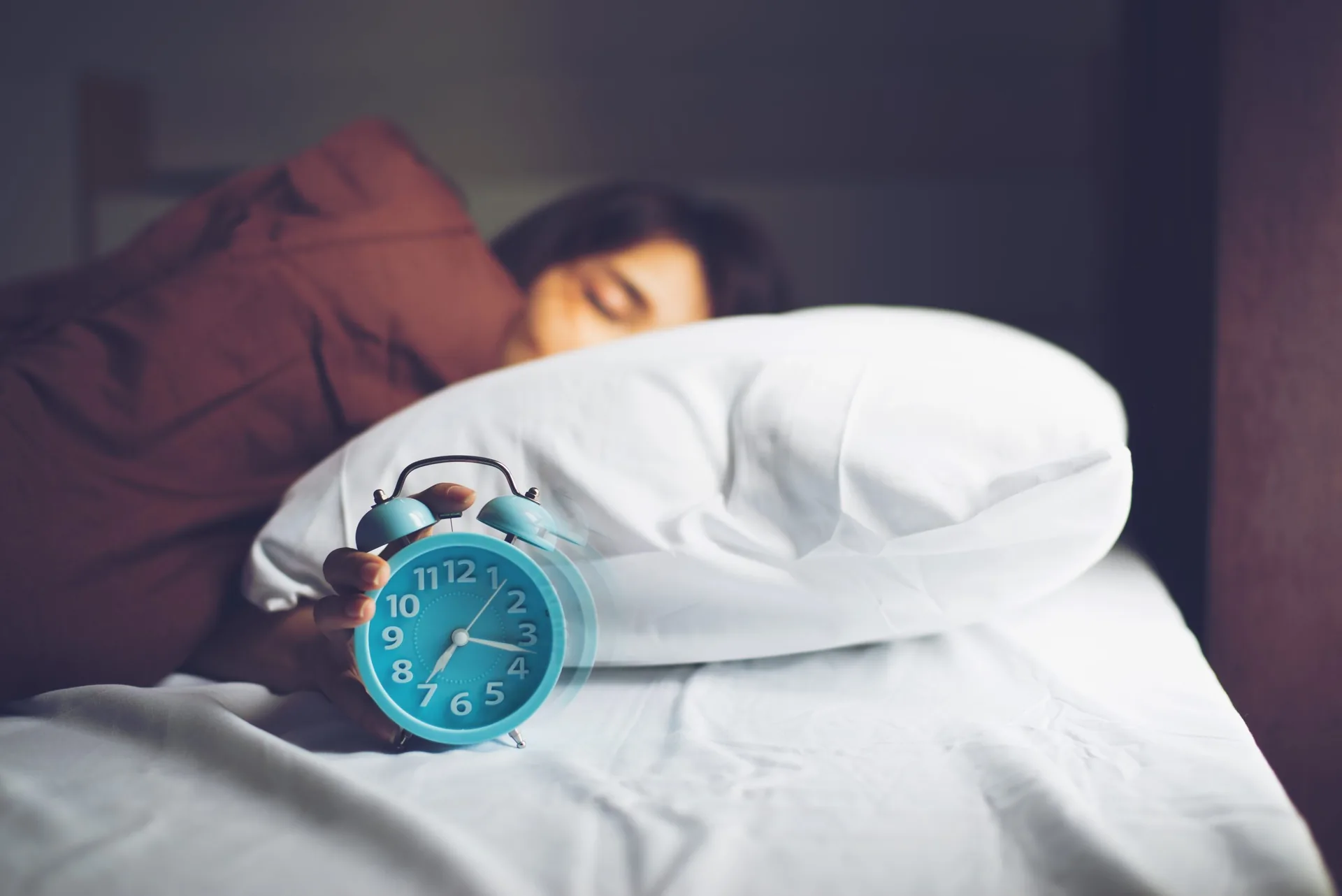 young-sleeping-woman-and-rise-hand-to-turn-off-alarm-clock