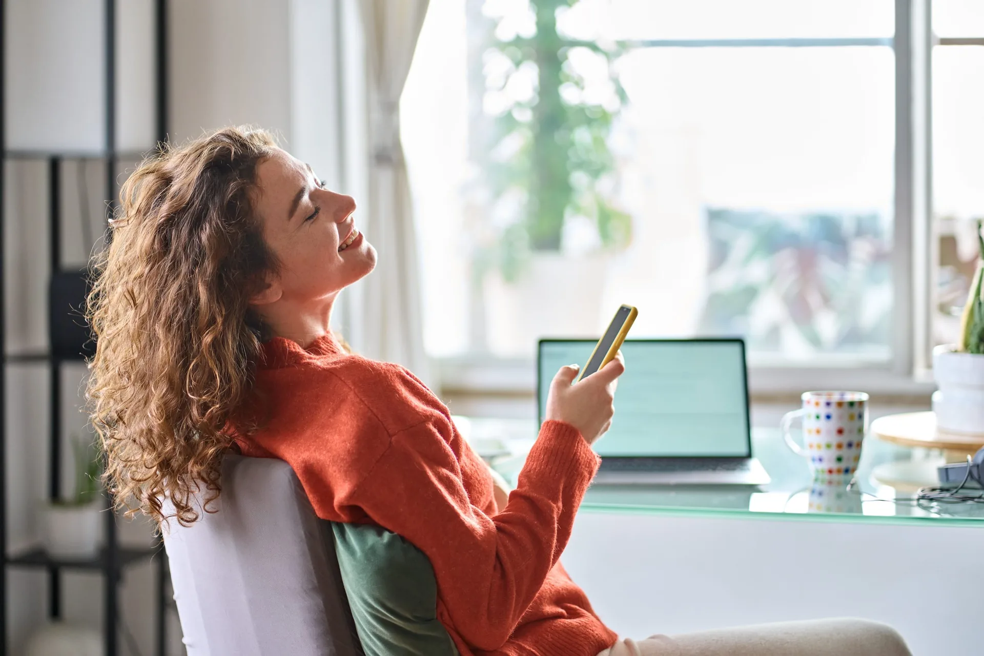 Young-smiling-pretty-woman-holding-smartphone-using-cell-mobile-phone-taking-break