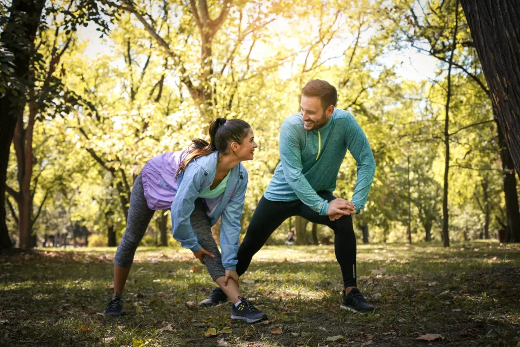 couple-stretching-park-young-working-exercise