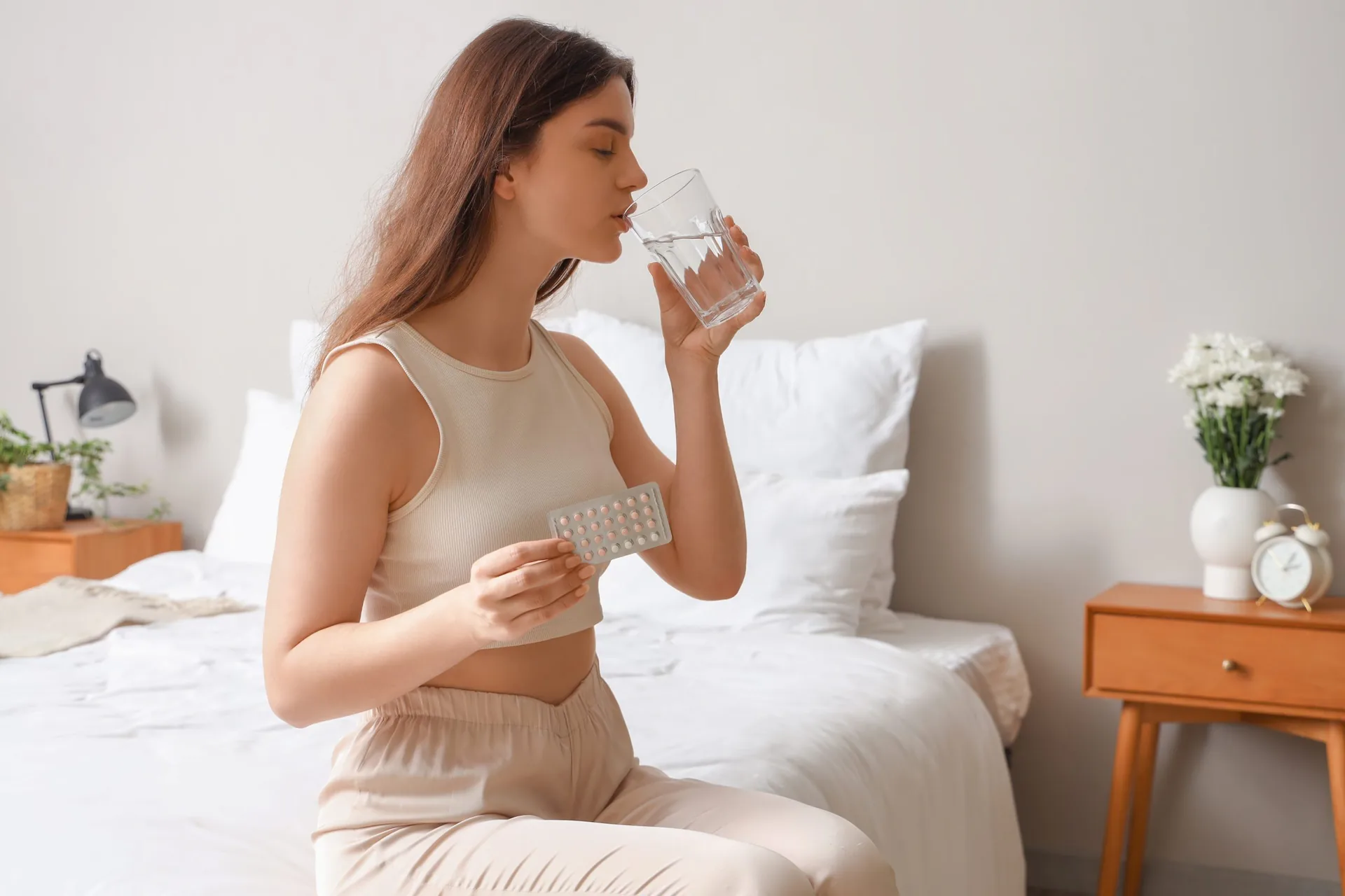 young-woman-taking-contraceptive-pills-glass