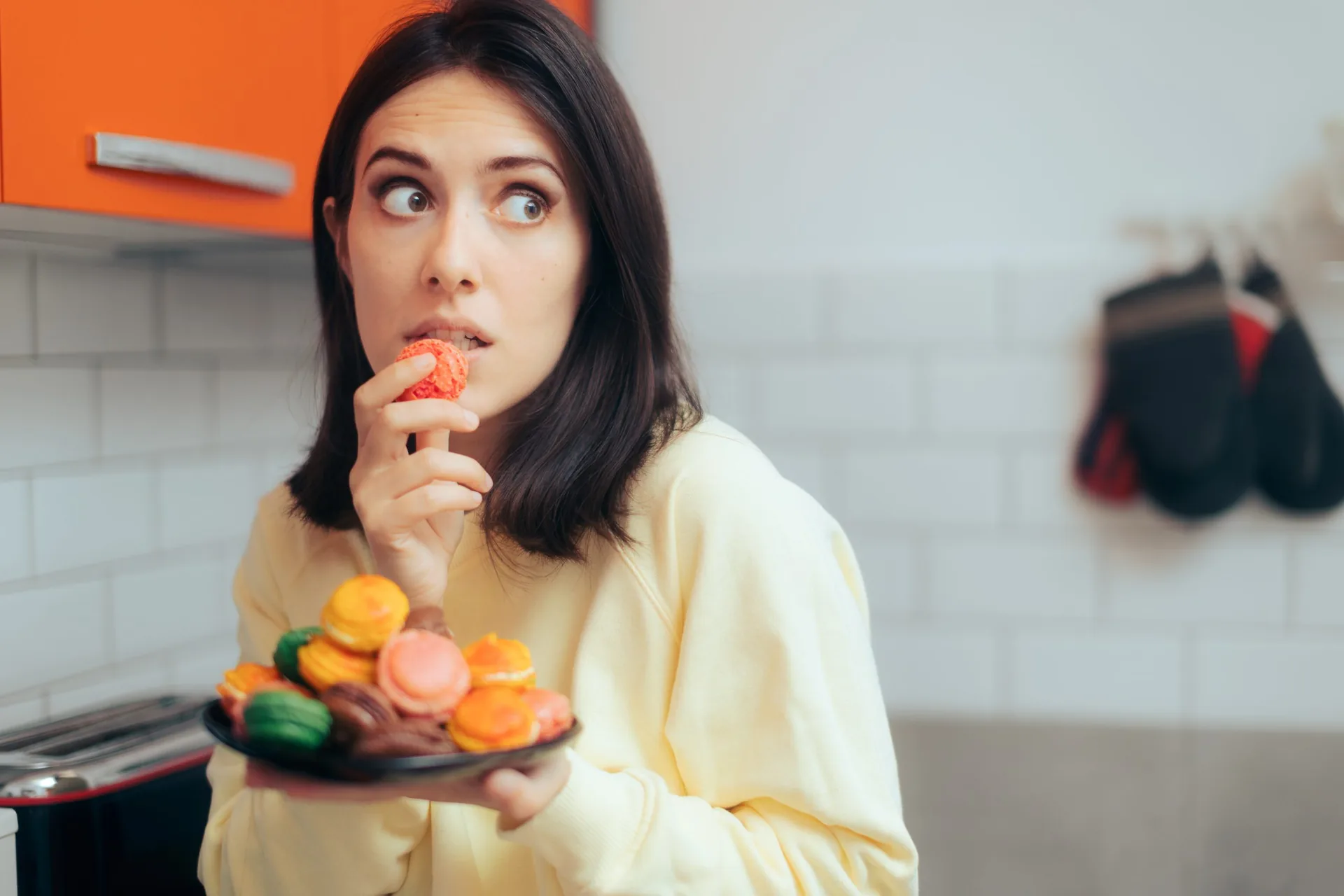 woman-eating-macarons-feeling-guilty-hiding